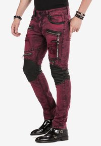 Burgunderfarbene Skinny Jeans mit distressed Akzenten, Reißverschluss-Taschen und schwarzen Knieeinsätzen. Verfügt über metallische Beschläge und Kettendetails.