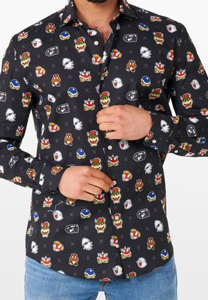 Schwarzes Oberhemd mit bunten Super Mario-Figuren wie Bowser, Goomba, Boo und Bullet Bill überall darauf, getragen von einem Mann, der es zuknöpft.