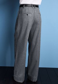 Gray wool trousers with a high waist and wide legs. Finished with a rolled hem, rear pockets, and a black leather belt.