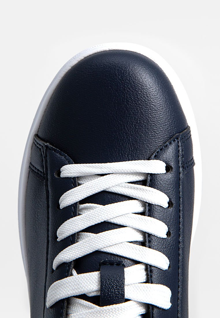 Baskets en cuir bleu marine avec un bout arrondi, des lacets blancs et une texture lisse. Présentent des coutures renforcées et une semelle en caoutchouc blanche.