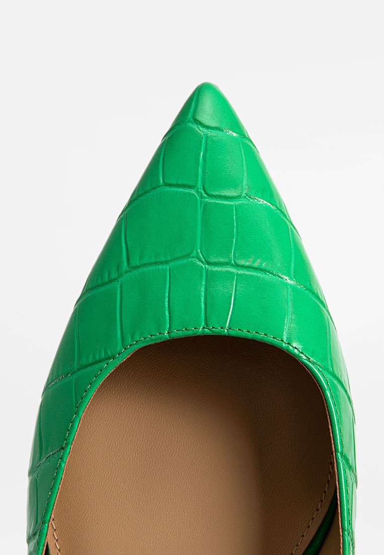 Zapato verde de punta afilada con un acabado brillante y textura de cocodrilo. El interior presenta un forro beige. Detalles de costura a lo largo de los bordes.