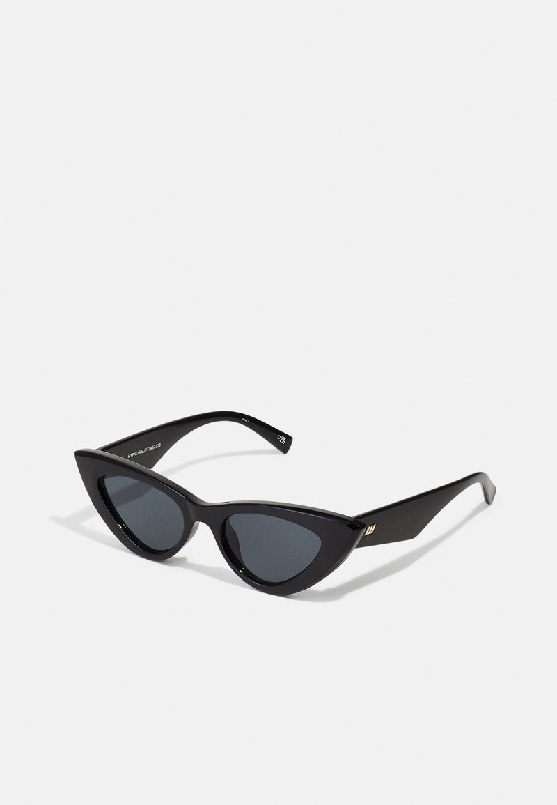 Óculos de sol estilo gato com uma armação de plástico preto brilhante, lentes escuras e detalhes em dourado nas hastes. Design angular com linhas elegantes.