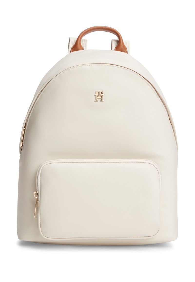 Ανοιχτό κρεμ σακίδιο με ομαλή υφή, καφέ δερμάτινες λεπτομέρειες, εμπρόσθια τσέπη με φερμουάρ και χρυσό λογότυπο μπροστά. Στρογγυλεμένο σχήμα.