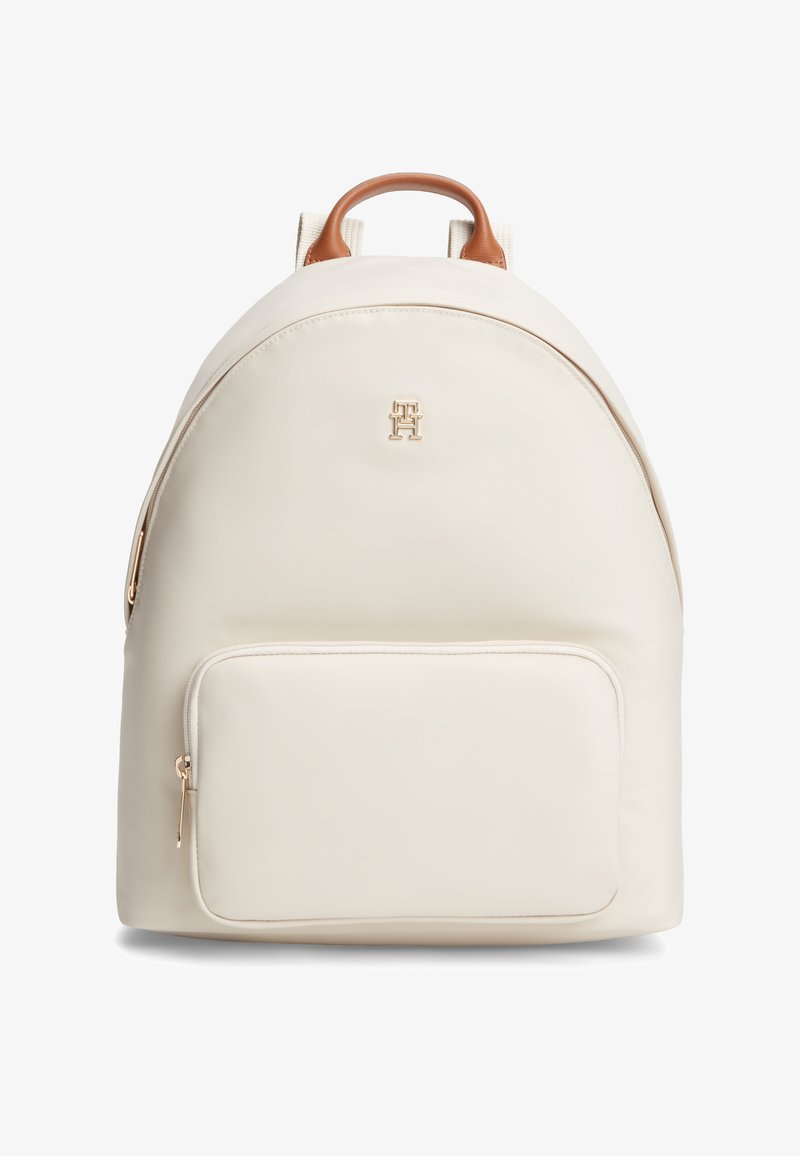 Ανοιχτό κρεμ σακίδιο με ομαλή υφή, καφέ δερμάτινες λεπτομέρειες, εμπρόσθια τσέπη με φερμουάρ και χρυσό λογότυπο μπροστά. Στρογγυλεμένο σχήμα.