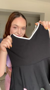 Zwarte jurk met een uitlopende rok, voorzien van een witte rand langs de halslijn. De stof lijkt glad en rekbaar.