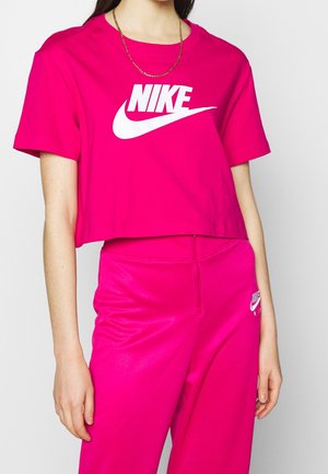 T-shirt Nike rose crop avec logo blanc, manches courtes, accompagné d'un pantalon rose brillant assorti avec un petit logo sur la hanche.