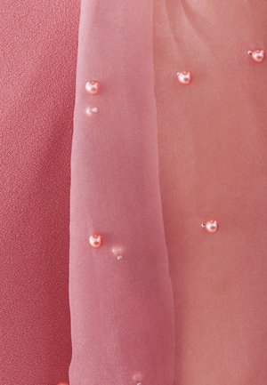 Tissu rose transparent orné de perles roses et blanches dispersées sur un matériau texturé rose rosé.