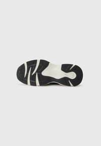 Zwarte buitenzool van een sneaker met witte accenten, voorzien van een gestructureerd patroon en een centraal logodetail. Gebogen lijnen voor grip.