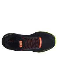 Scarpa da ginnastica nera con tomaia in tessuto testurizzato, dettagli rossi e suola di un brillante verde. Presenta lacci standard e un colletto imbottito.