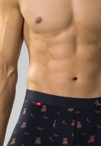 Czarne bokserki z wzorem przedstawiającym niedźwiedzia i serca, elastyczny pas z metką logo oraz miękka bawełniana mieszanka dla komfortu.