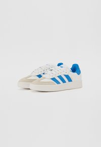 Pair of white and blue Adidas Samba sneakers with suede toe caps, blue stripes, and white laces on a plain white background.