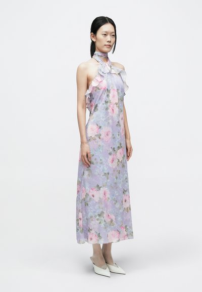 Hosszú, orgonalila virágmintás ruha fodros nyakkivágással és pántos megkötővel. Rózsaszín rózsákkal és zöld levelekkel díszítve, fehér hegyes orrú lapos cipővel párosítva.