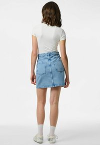 Heled sinine teksaseelik, millel on rebenenud ääred, kaks tagataskut ja keskmise kõrgusega piht, kantud istuva valge lühikese varrukaga toppiga.