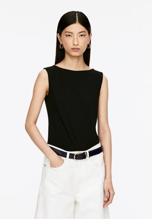 Black sleeveless top made of soft fabric, featuring a boat neckline. Worn with white pants and a navy belt, showcasing a polished look.