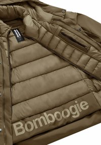 Interno di giacca a vento marrone con texture trapuntata, con un prominente logo "Bomboogie". Include una tasca con zip e un'etichetta di cura.