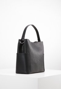 Sort håndtaske med en struktureret slangeskindsstruktur, glatte sorte læderdetaljer, enkelt håndtag og en sidelomme for ekstra funktionalitet.