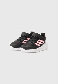 Chaussures de sport noires avec des rayures roses, dotées d'une tige en maille respirante, d'une sangle Velcro et d'une semelle en caoutchouc blanche.