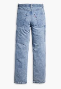Jeans de mezclilla azul claro con piernas rectas, dos bolsillos traseros, bolsillos laterales para herramientas y una etiqueta roja visible en el bolsillo trasero derecho.