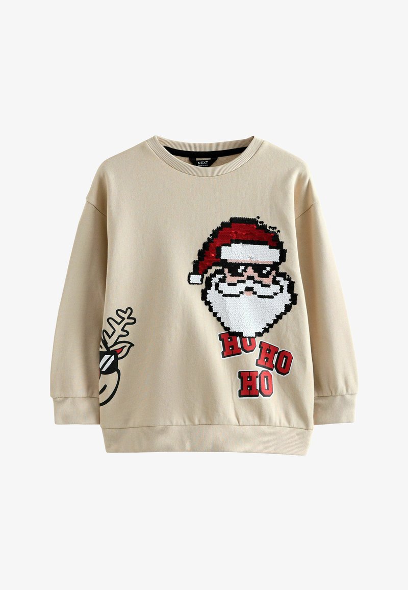 Bēšas krāsas džemperis ar pikseļu stila Ziemassvētku vecīša attēlu, kurš valkā saulesbrilles, uzraksts "HU HO HO" un stilīgs ziemeļbrieža grafikas attēls uz piedurknes.