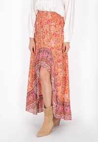 Oranje bloemen maxi rok met een high-low zoom en decoratieve rand. Ontworpen met een gerimpelde tailleband en gecombineerd met beige enkelboots.