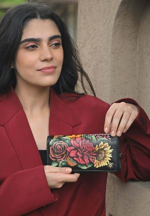 Zwarte portemonnee met een levendig bloemdesign met rode, roze en gele bloemen. Gladde textuur met een omslagsluiting en gouden accenten.