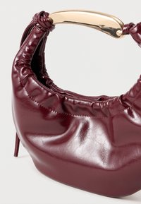 Μπορντώ τσάντα από faux δέρμα με συγκεντρωμένη υφή και χρυσό μεταλλικό χερούλι. Διαθέτει στρογγυλή σχήμα και ελάχιστες ραφές.