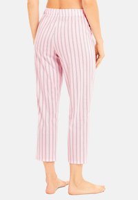 Pyjamabroek van lichtroze stof met verticale strepen in donkerroze en blauw. Heeft een elastische tailleband en een cropped lengte.