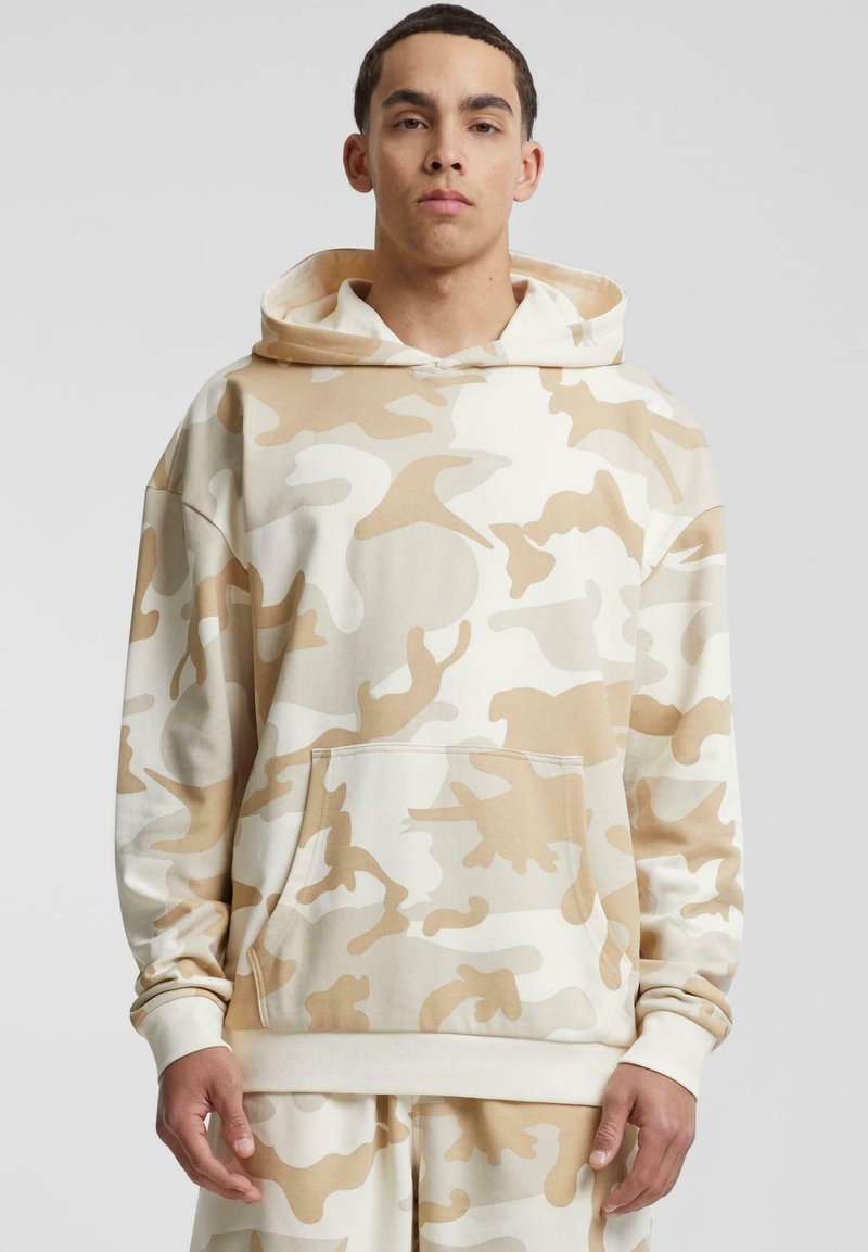 Beige kamuflasje hettegenser laget av myk stoff. Har en frontlomme, stor hette, og ribbestrikkede mansjetter og nederkant. Avslappet passform design.