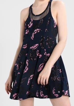 Sleeveless navy dress with pink and black leaf patterns and sheer mesh neckline worn by a person with fair skin.