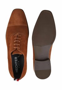 Bruine suède schoenen met een puntige neus, zes oogjes vetersluiting en een platte rubberen zool. Het interieur heeft het "HECHTER PARIS" merk.