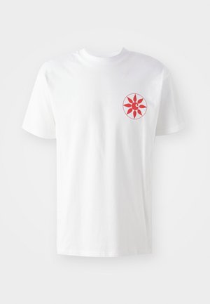T-shirt en coton blanc avec un motif de soleil rouge sur la poitrine gauche. Manches courtes, col rond et texture douce. Design simple et épuré.