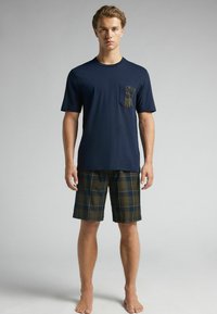 Marinblå t-shirt med bröstficka som har ett rutmönster; matchande rutig shorts i mörkgrön, guld och marinblå; avslappnad passform.