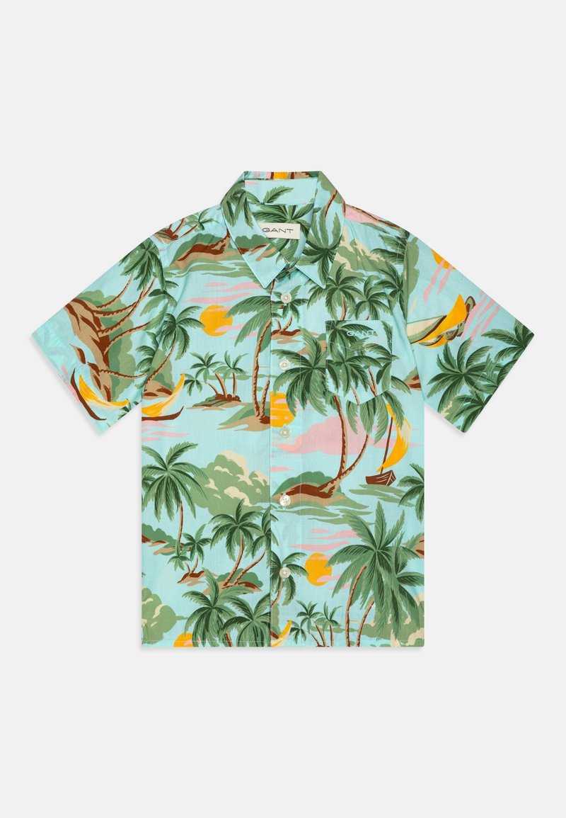 Chemise à manches courtes à boutons avec imprimé tropical multicolore comprenant des palmiers, des soleils jaunes et des voiliers sur fond bleu clair.