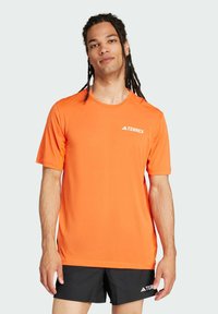 Camiseta deportiva TERREX de color naranja brillante, con mangas cortas, cuello redondo y tejido ligero. Detalle mínimo de logo blanco en el pecho.