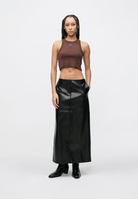 Καφέ κομμένο τοπ και μαύρη δερμάτινη φούστα maxi με πλαϊνές τσέπες. Ομαλή υφή, εφαρμοστή σχεδίαση με ευθεία σιλουέτα, συνδυασμένη με μαύρες μπότες.
