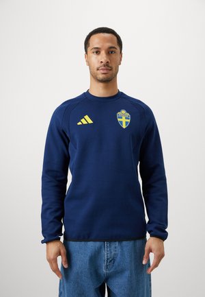 Sweatshirt azul-marinho com mangas longas, gola redonda, punhos canelados e detalhes amarelos. Apresenta o logótipo da seleção nacional da Suécia no peito.