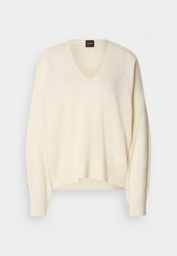 Maglione a V crema realizzato in tessuto morbido, con maniche ampie, vestibilità rilassata e dettagli in lavorazione a maglia discreti all'orlo e sulle spalle.