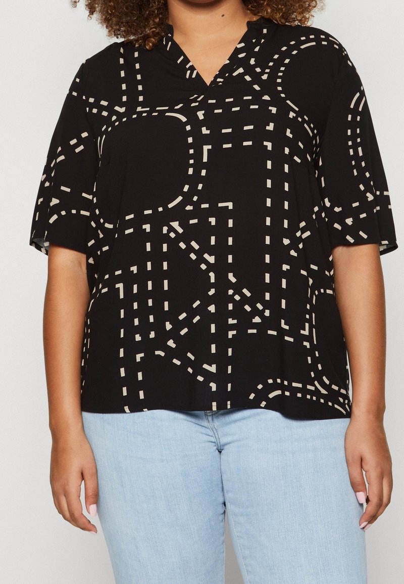 Svart blus med V-ringning och korta ärmar, prydd med ett beige geometriskt mönster som liknar streckade linjer och vägkartor.