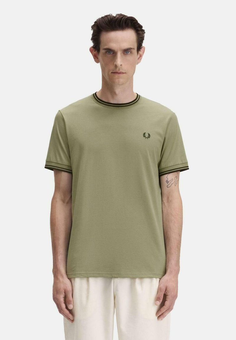 T-shirt en coton vert olive avec col rond et manches courtes ; présente un bord-côte vert foncé et un petit logo brodé sur la poitrine.