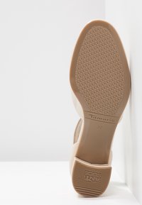 Beige podeševka vysokých podpatků s texturovaným vzorem z gumy pro lepší grip. Disponuje blokovým podpatkem a vyraženým názvem značky "Tamaris" s velikostí 37.