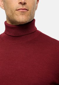 Bordeauxfarbener Rollkragenpullover, gerippte Textur, taillierte Passform, hoher Kragen und nahtlose Details um den Hals und die Schultern.