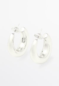 Silver metallringar i form av örhängena, med en slät, rund design och en polerad yta samt fäste med spik.