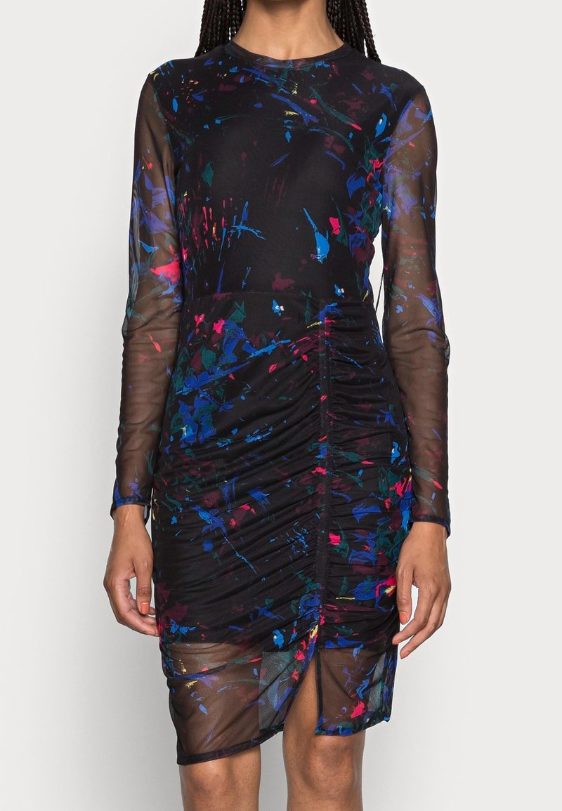 Zwarte jurk met lange doorschijnende mouwen, voorzien van kleurrijke spetterpatronen, geplooide textuur en een hoge split tot boven de dij. Zachte stofafwerking.