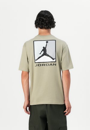 Olivgrön bomull t-shirt med en stor svart Jordan-logotypgrafik på ryggen, korta ärmar och en avslappnad passform.
