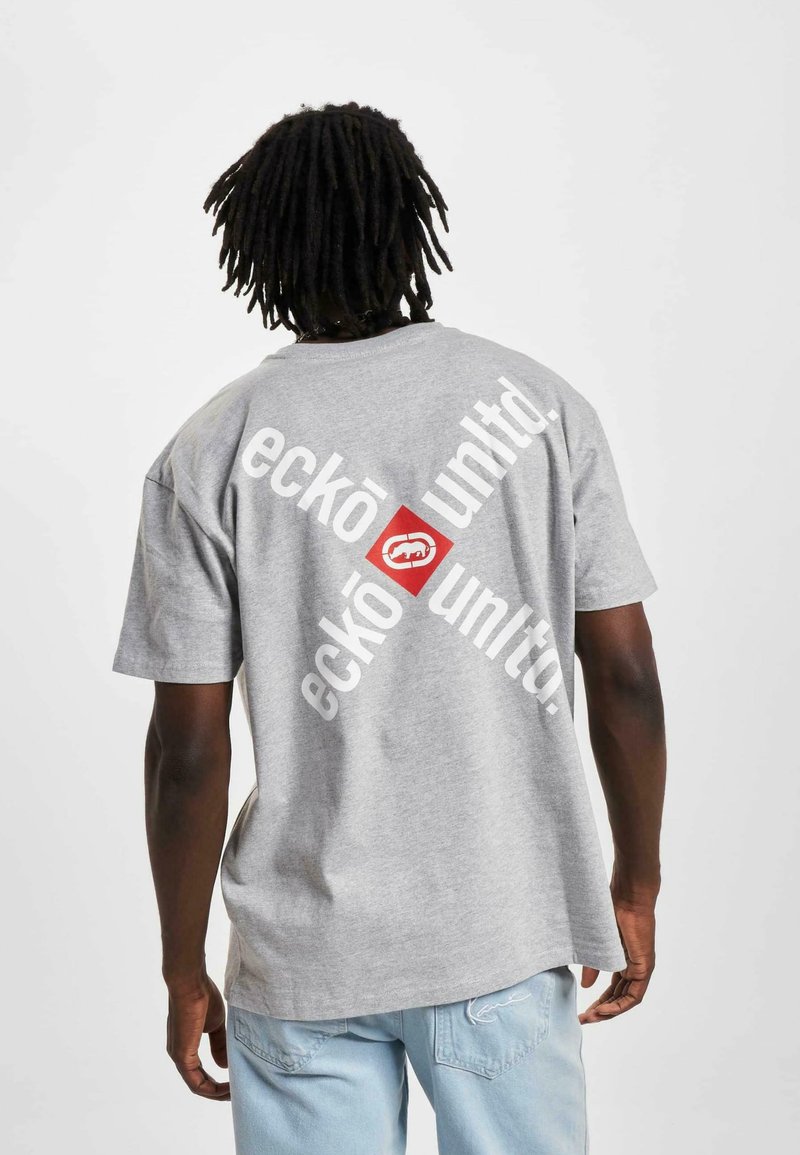 Grå bomull T-skjorte med et stort diagonalt grafikk som har teksten "eckō un1t3d." og en rød boks med logo på baksiden. Casual fit.