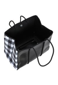 Mustavalkoinen ruudullinen kassi, jossa on perforoidut mustat sivut, musta sisustus ja kaksi mustaa kahvaa. Mukana on vetoketjullinen tasku sisällä.