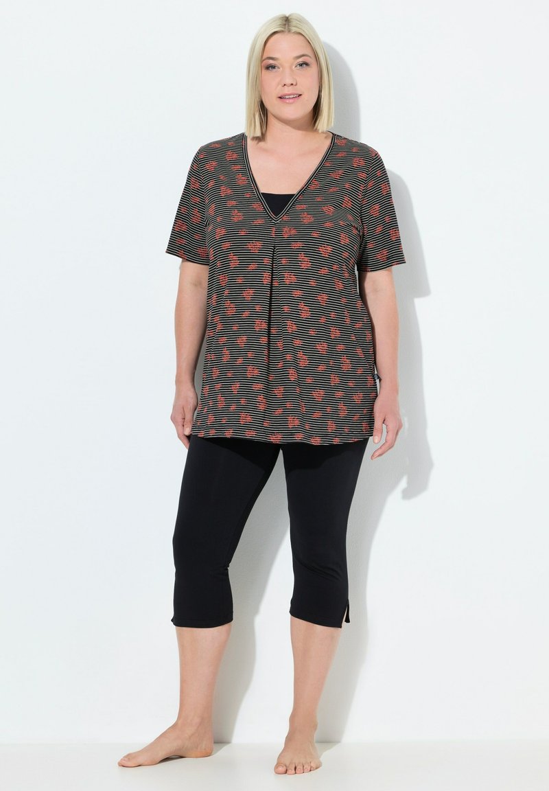 Túnica a rayas negras y rojas con patrón floral, escote en V, mangas cortas, combinada con leggins capri negros, con aberturas laterales en el dobladillo.