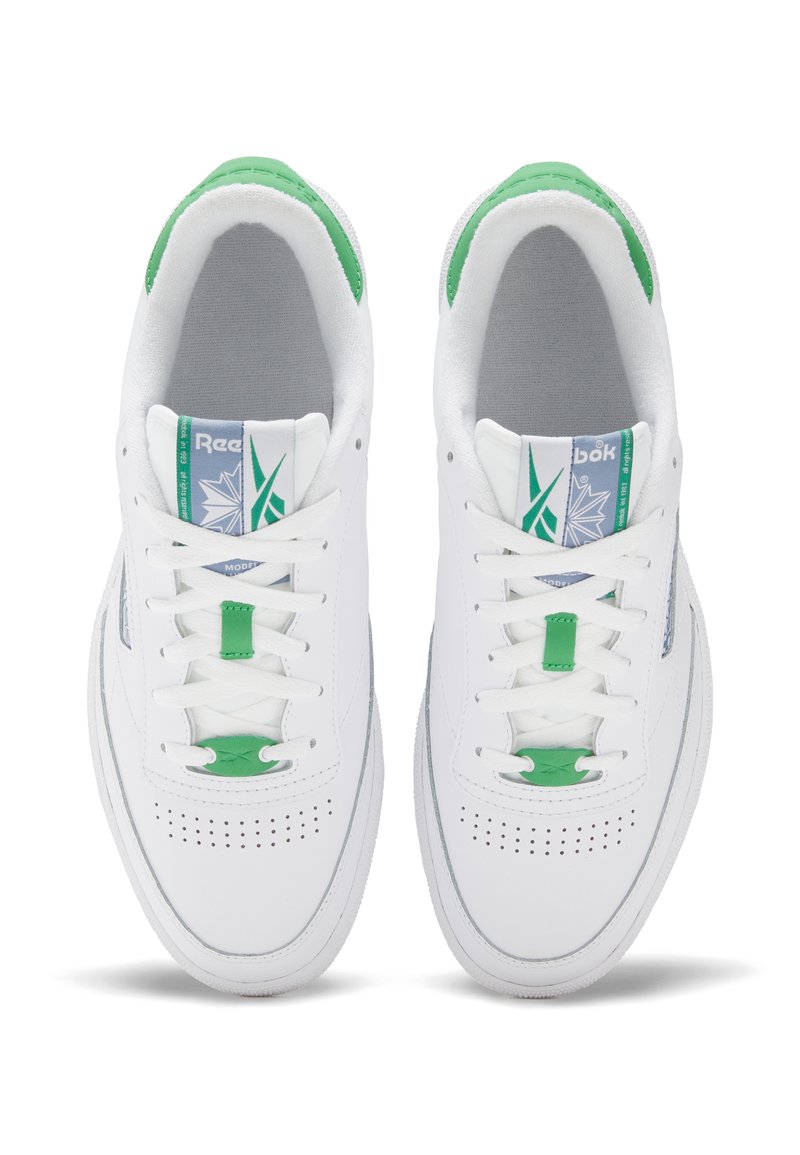 Ein Paar weiße Reebok-Sneaker mit grünen Akzenten und perforiertem Zehenbereich, von oben betrachtet vor einem weißen Hintergrund.