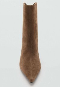 Bota de ante marrón hasta el tobillo con punta afilada y una silueta elegante, con una parte superior alta y recta sin herrajes ni detalles visibles.