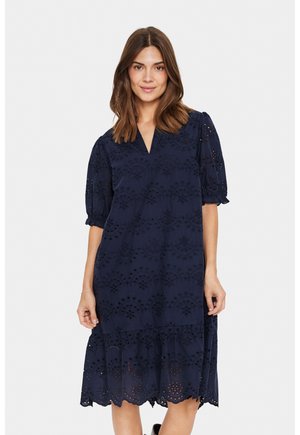 Navy blue dress with eyelet embroidery, V-neckline, short puff sleeves, and a tiered hem. Lightweight fabric with a slightly textured finish.